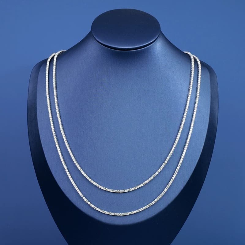 Two tennis chain necklaces on a blue jewelry display